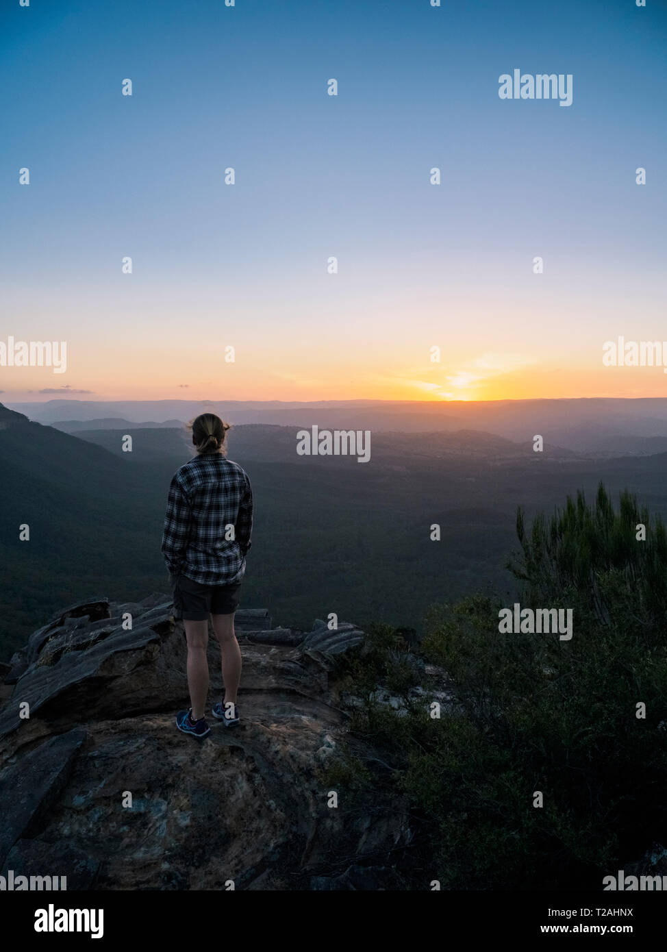 Donna in piedi sul picco di montagne blu all'alba del Nuovo Galles del Sud, Australia Foto Stock