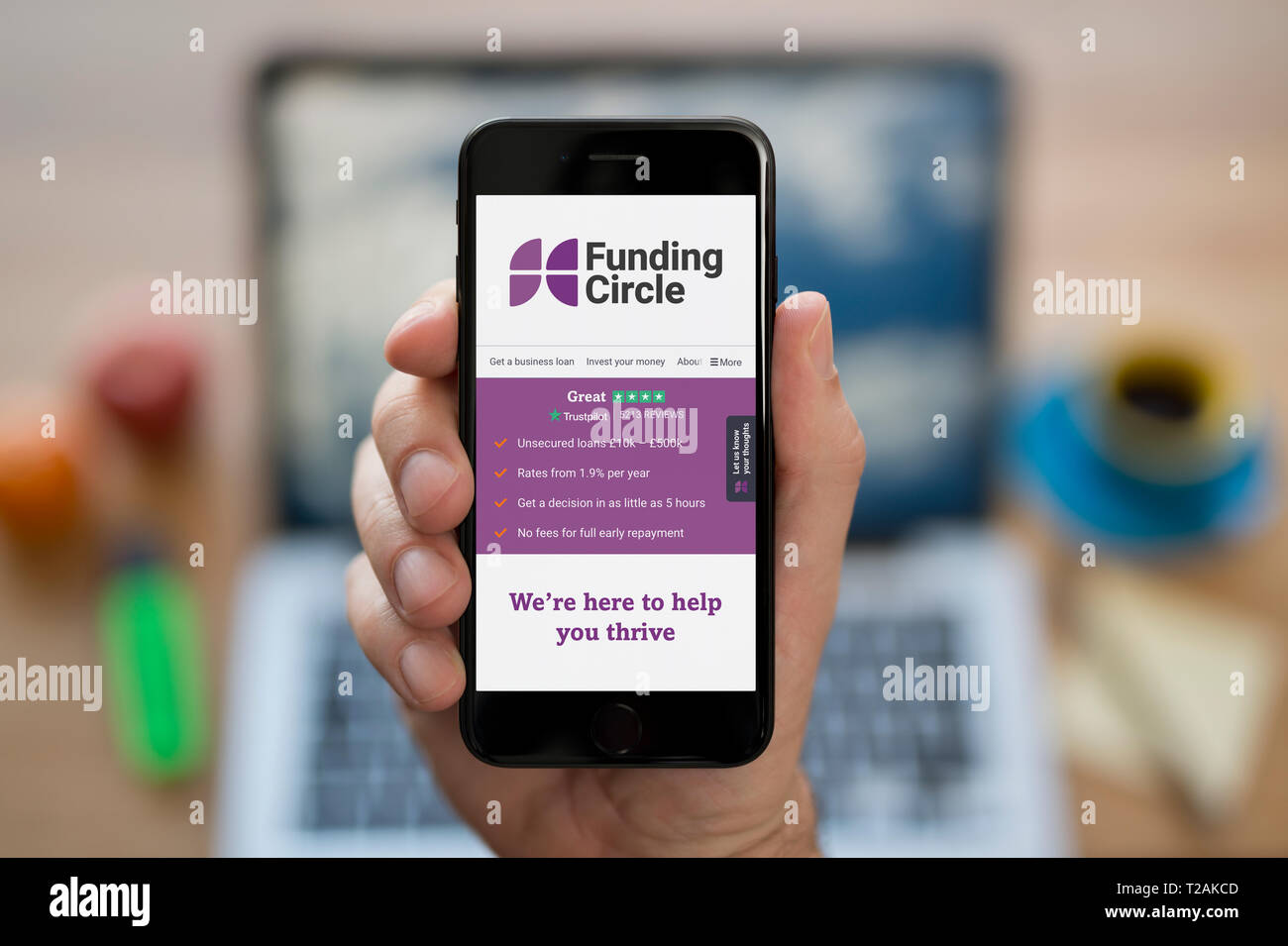 Un uomo guarda al suo iPhone che visualizza il finanziamento del logo a forma di cerchio (solo uso editoriale). Foto Stock