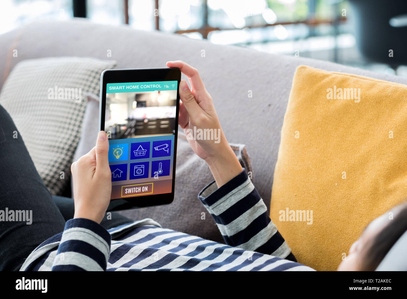 Smart home automation control concpet.donna sdraiata sul divano tablet utilizzando il dispositivo di comando in casa.La tecnologia digitale stile di vita. Foto Stock