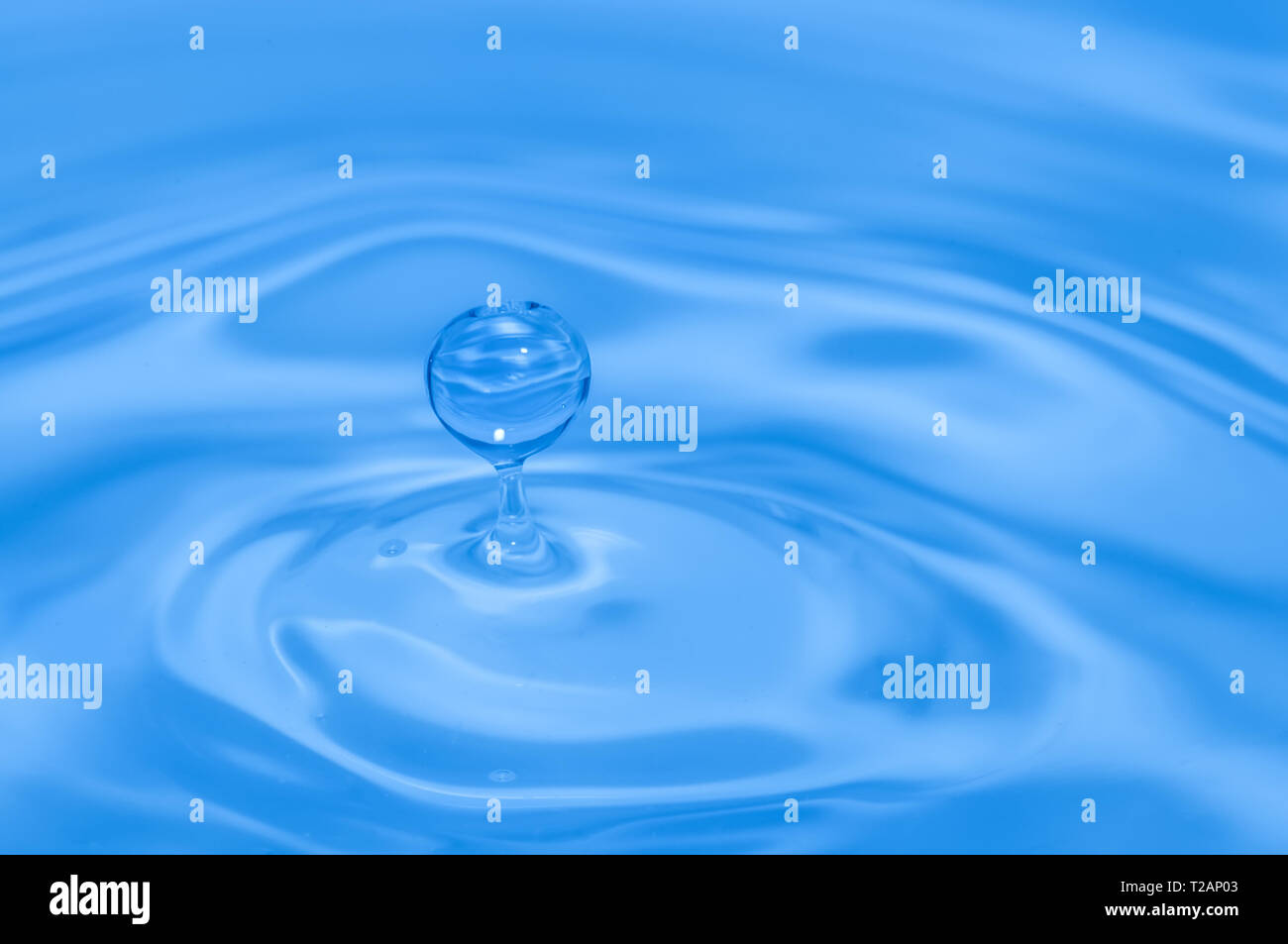 Luce di colore blu goccia d'acqua splash e increspature. Macro shot Foto Stock