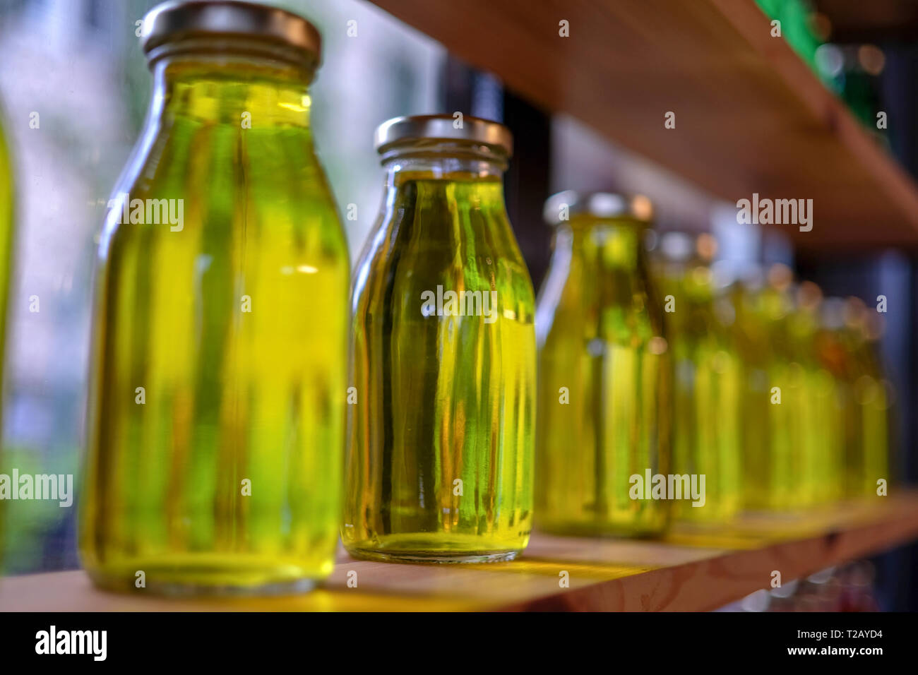 La luce riflessa attraverso le bottiglie di olio di oliva su un ripiano Foto Stock