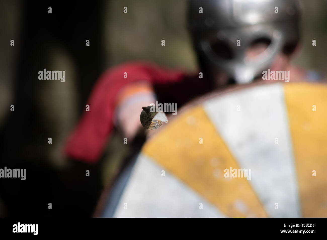 Viking dietro lo scudo rotondo indossando il comando del timone Germundbu che punta la punta affilata sulla fotocamera Foto Stock