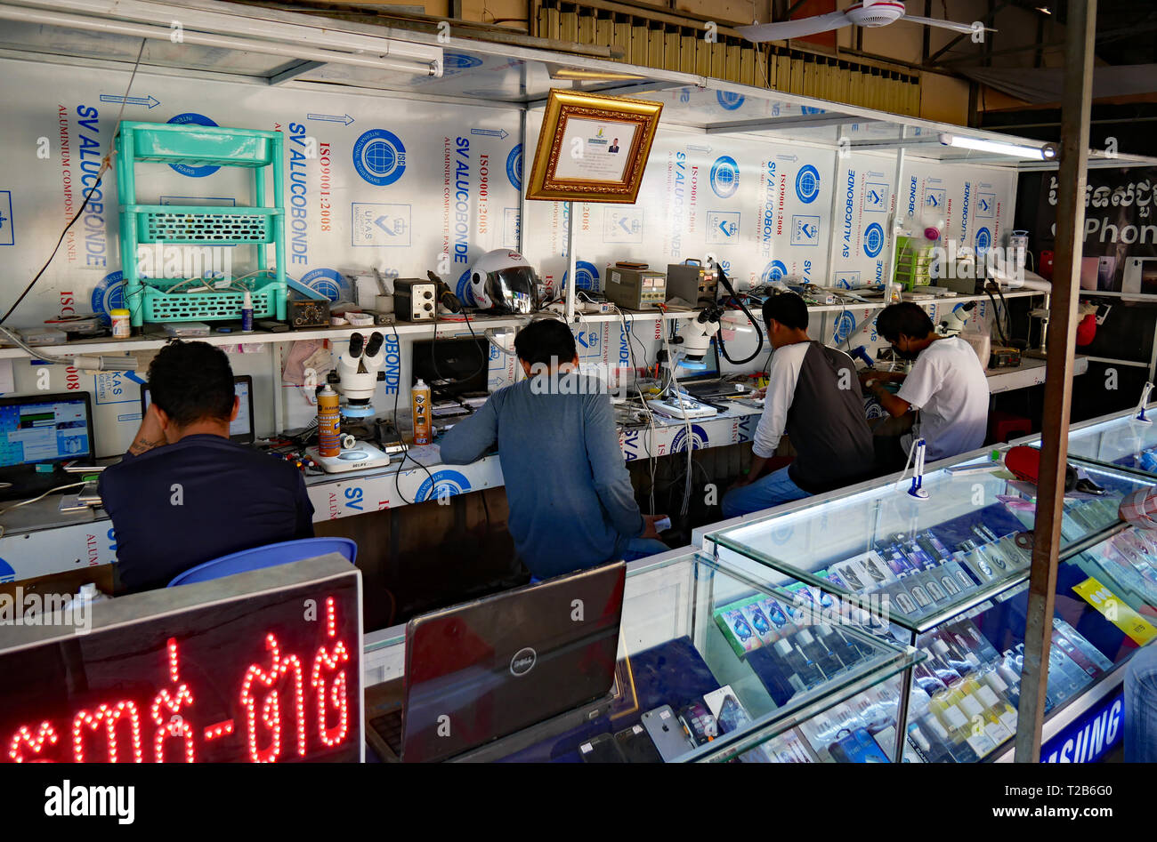 Battambang, Cambogia. I tecnici di riparazione telefoni mobili in un aperto Khmer fronteggiata phone shop. 15-12-2018 Foto Stock