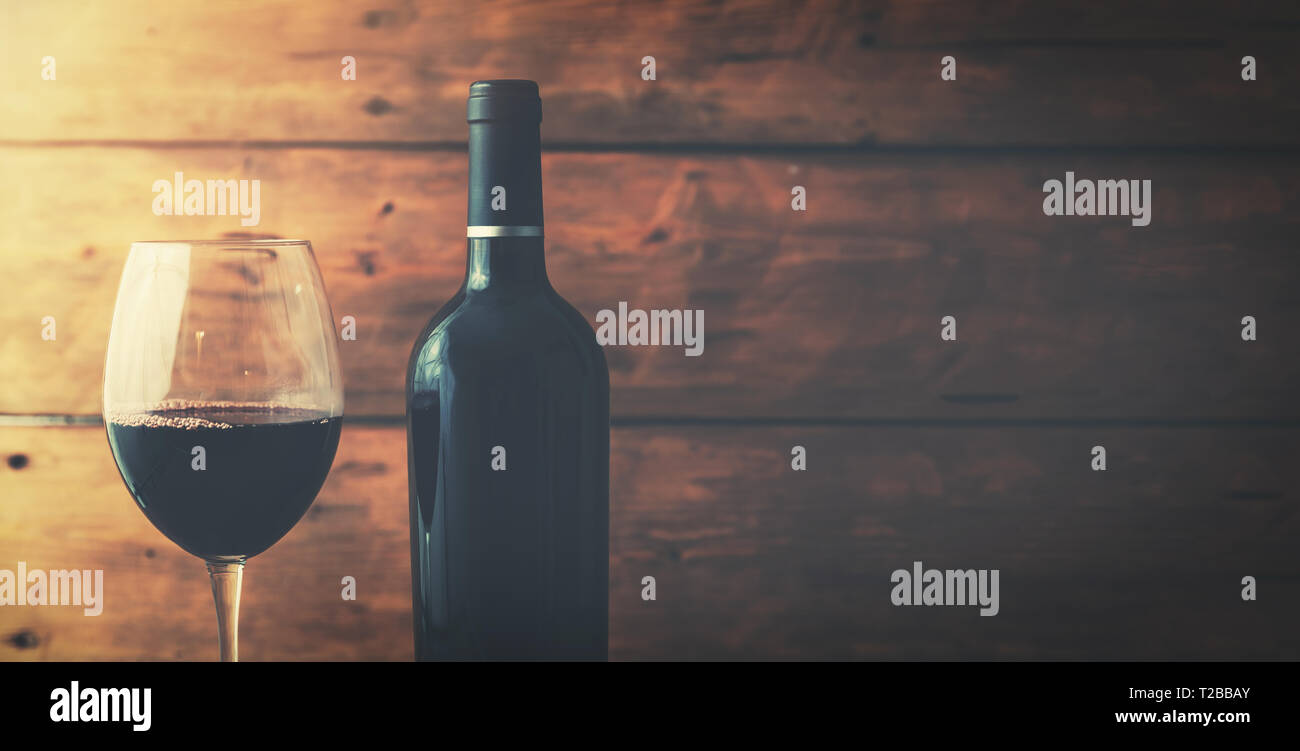 Vino rosso e bottiglia di vetro sul vecchio sfondo di legno con spazio di copia Foto Stock
