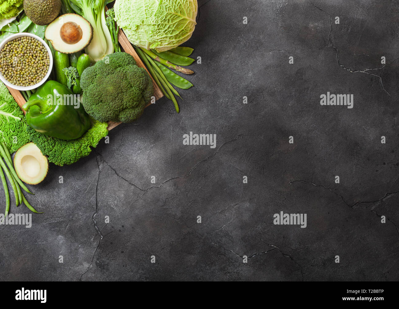 Assortiti nei toni del verde materie verdure organiche su sfondo scuro. Avocado, cavoli broccoli, cavolfiori e cetriolo con fagioli rifilati. Foto Stock