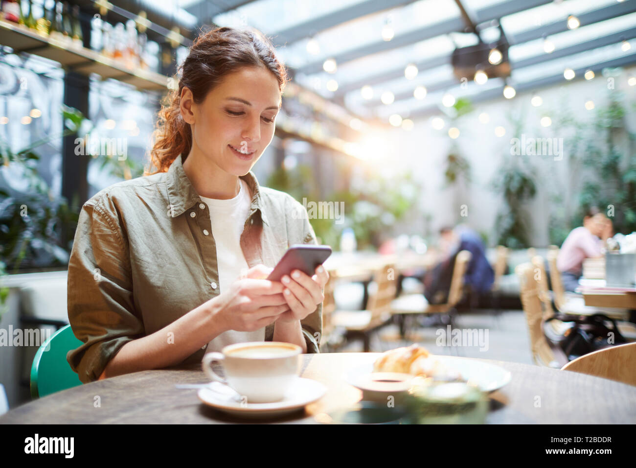 Pretty Woman controllo messenger in cafe Foto Stock