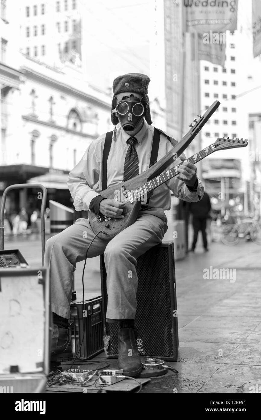 Suonatore ambulante di strada di suonare una chitarra con una maschera a gas. Foto Stock