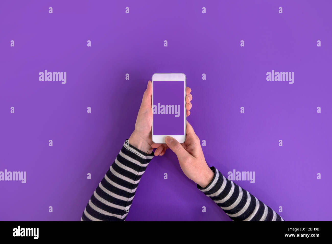 Smartphone nelle mani femminili mock up top view copia spazio su sfondo a raggi ultravioletti Foto Stock