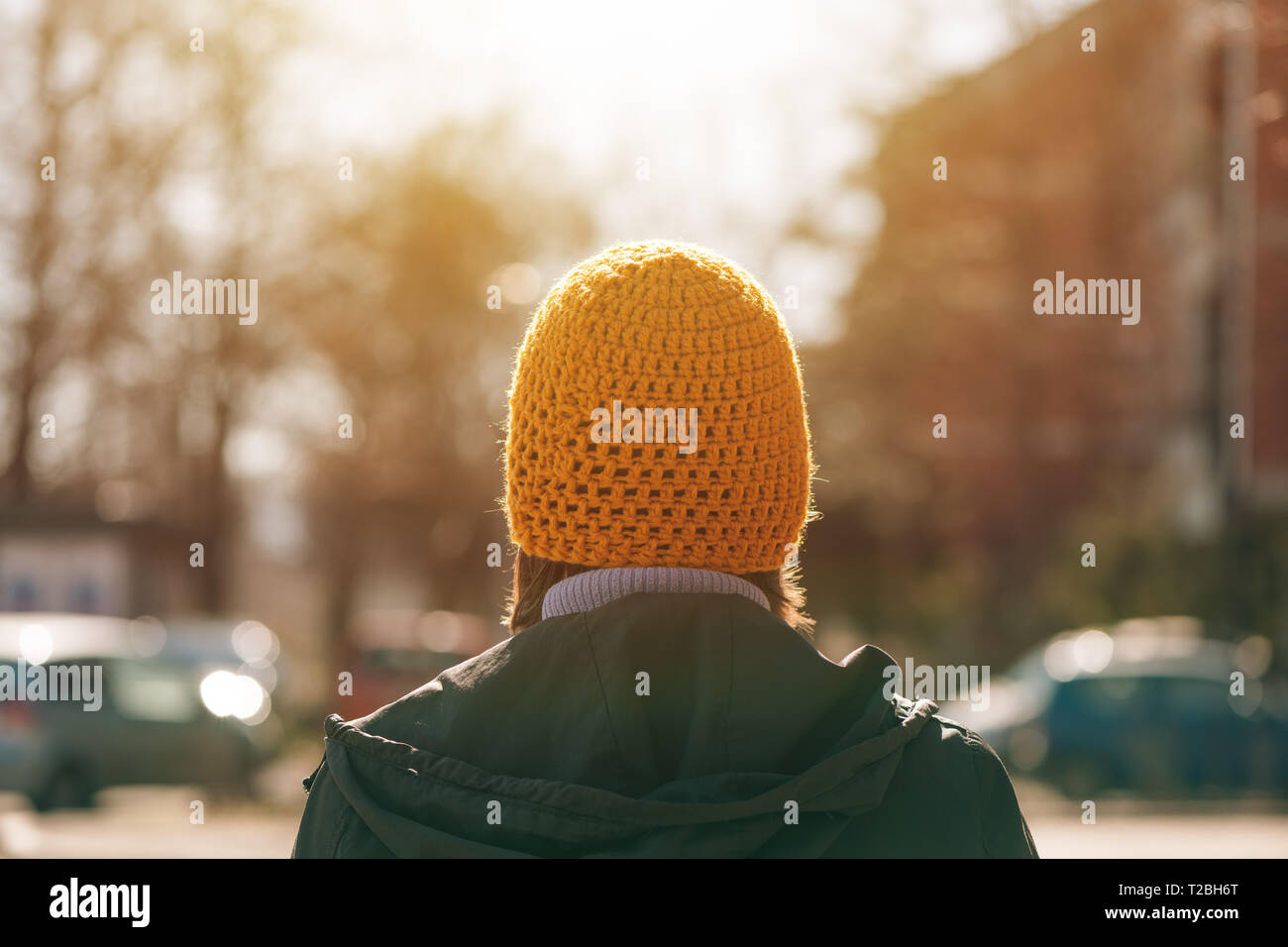 Vista posteriore del casual donna chi cammina sulla strada nella soleggiata mattina di primavera Foto Stock