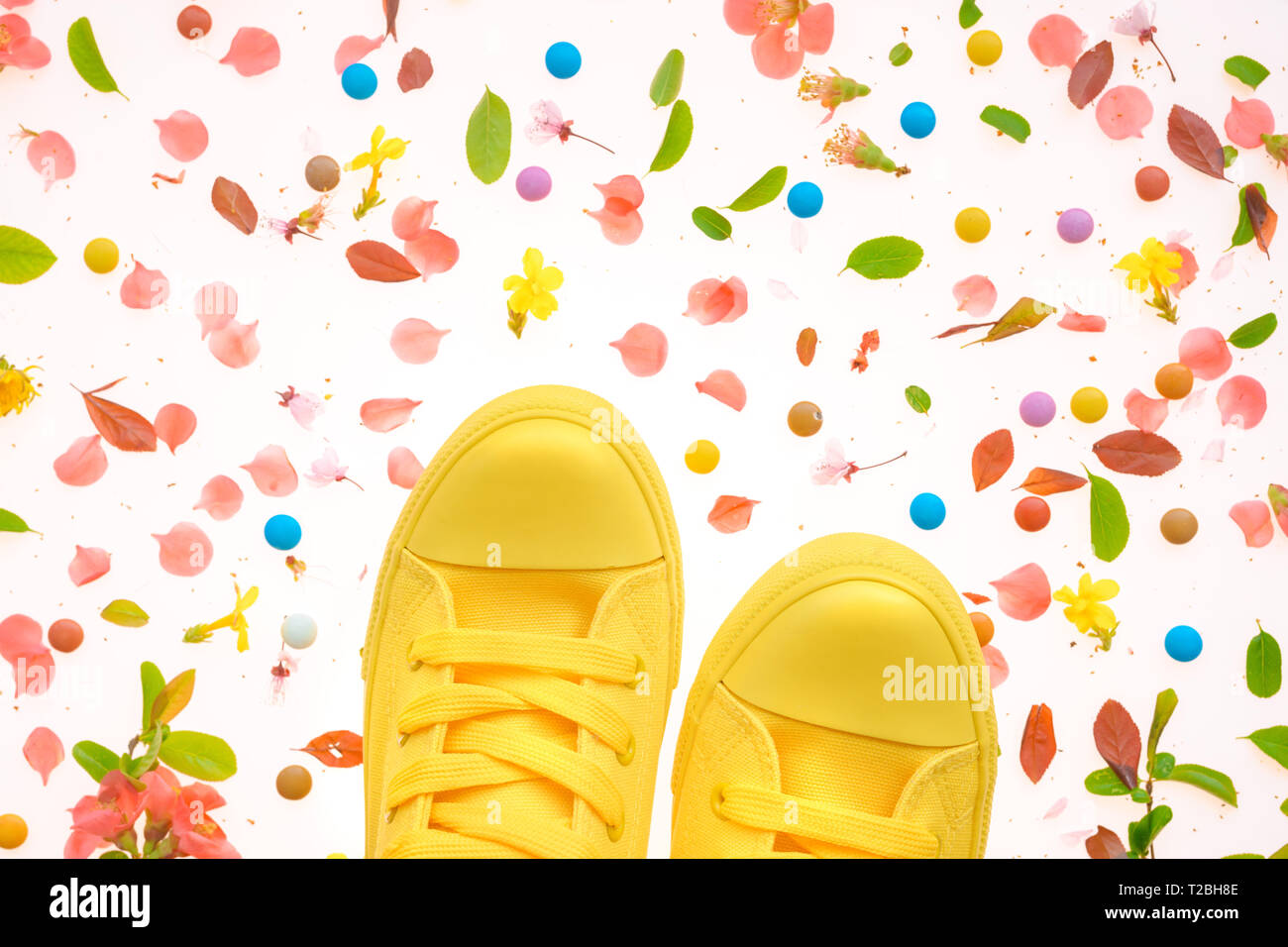 Sneakers giallo sulla colorata primavera superficie decorata, vista dall'alto lay piatto Foto Stock