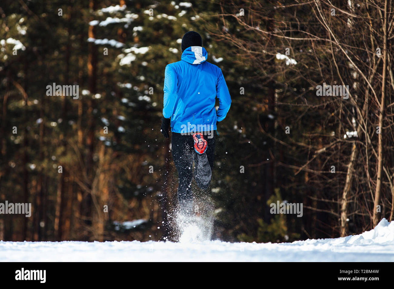Torna atleta runner acceso sentiero invernale neve spray mosche Foto Stock