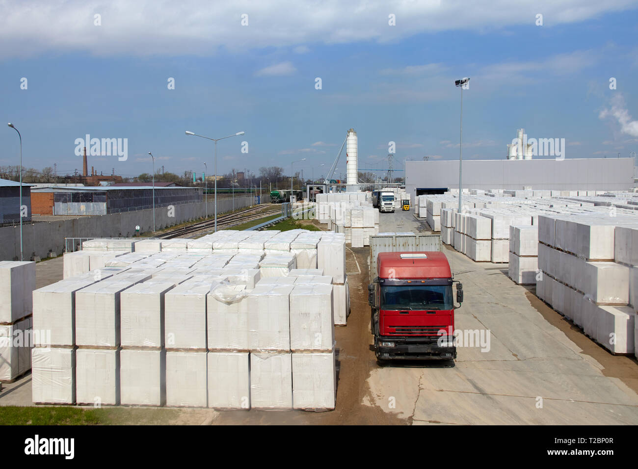 Vista della fabbrica di produzione di vegetali autoclavato calcestruzzo aerato. Molti pacchetti di blocchi su pallet mettere uno sull'altro in un magazzino esterno. Carrello ri Foto Stock