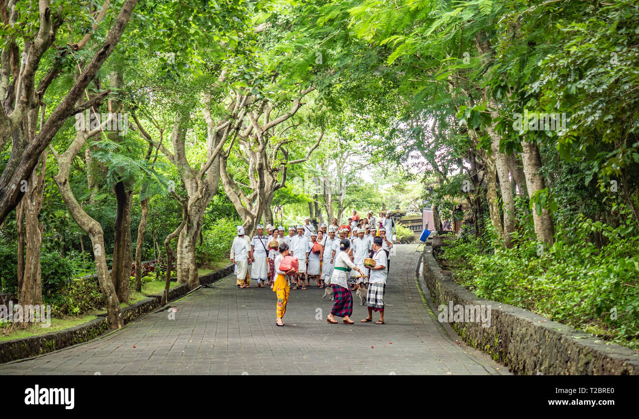 Popolo Balinese, famiglie locali, indossa tutto bianco, in processione alla pura Luhur Tempio di Uluwatu, andando a pregare e a donare alimenti di mare spiriti. Bali Foto Stock