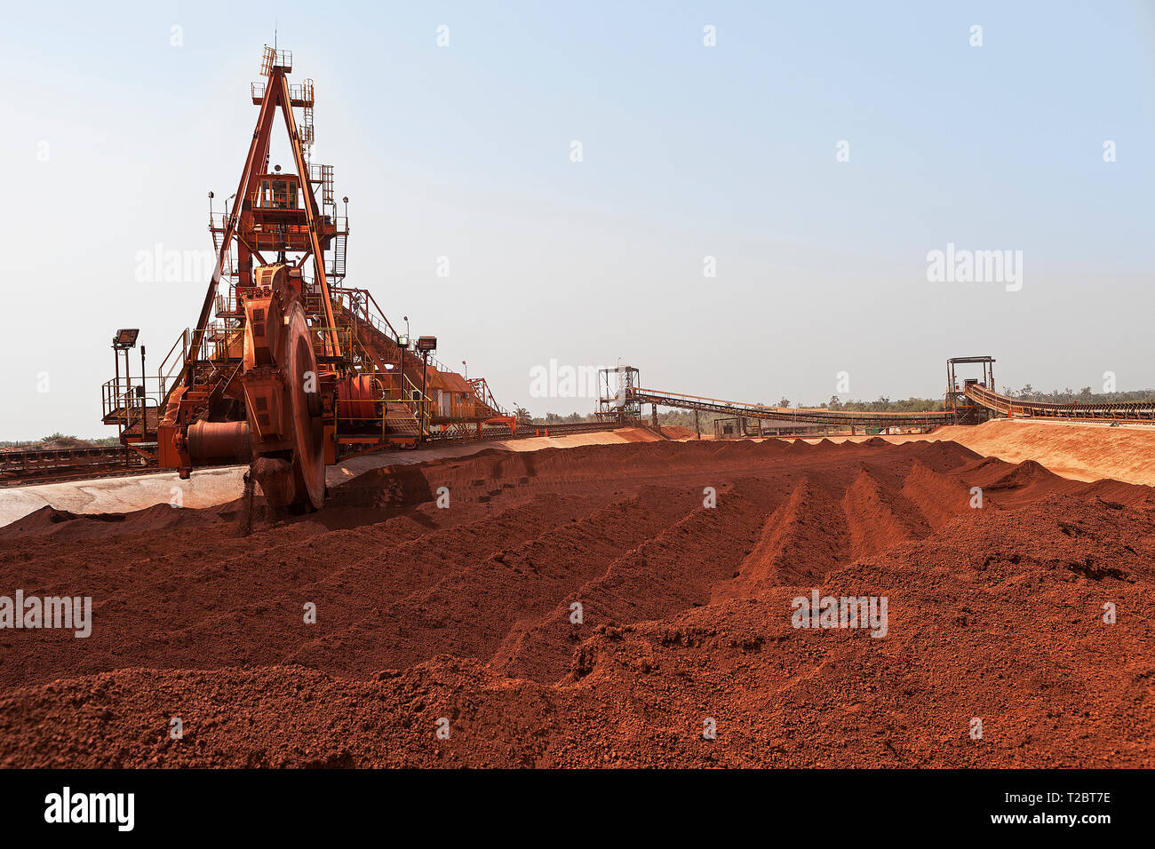 Operazioni portuali per la gestione e il trasporto di minerale di ferro. La benna ruota raccoglitore reclaimmer utilizzando cucchiai per il minerale di stack da stock sul nastro per la spedizione Foto Stock
