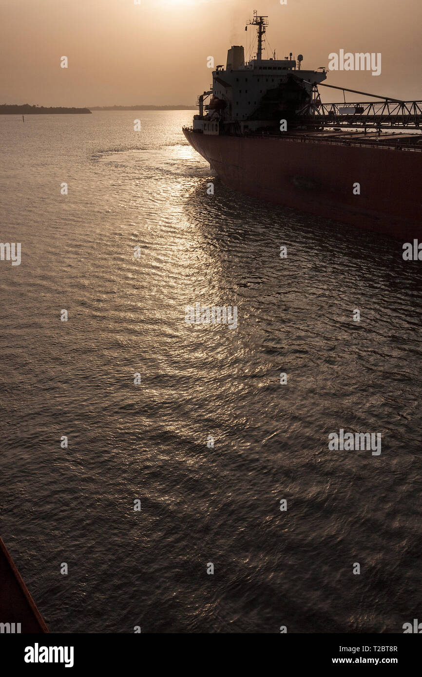 Operazioni portuali per la gestione e il trasporto di minerale di ferro. Sunrise attraverso il ponte e trattiene il minerale di ferro trasbordo vaso mentre il docking e prima del caricamento Foto Stock