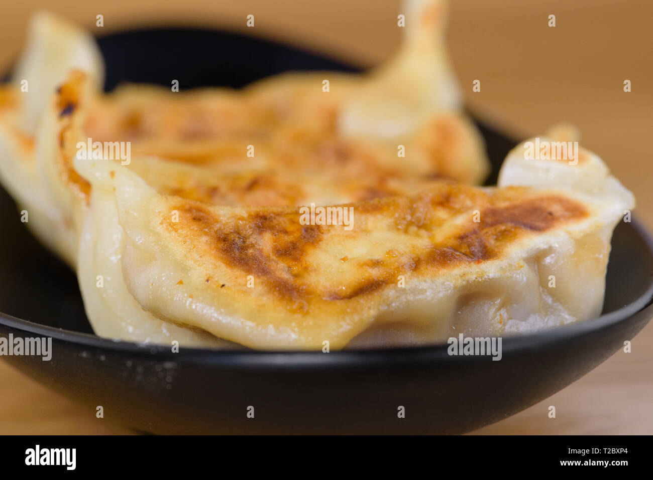 Grigliata ravioli giapponese servita su una piastra nera, con ripieno di carne, gyoza ricetta Foto Stock