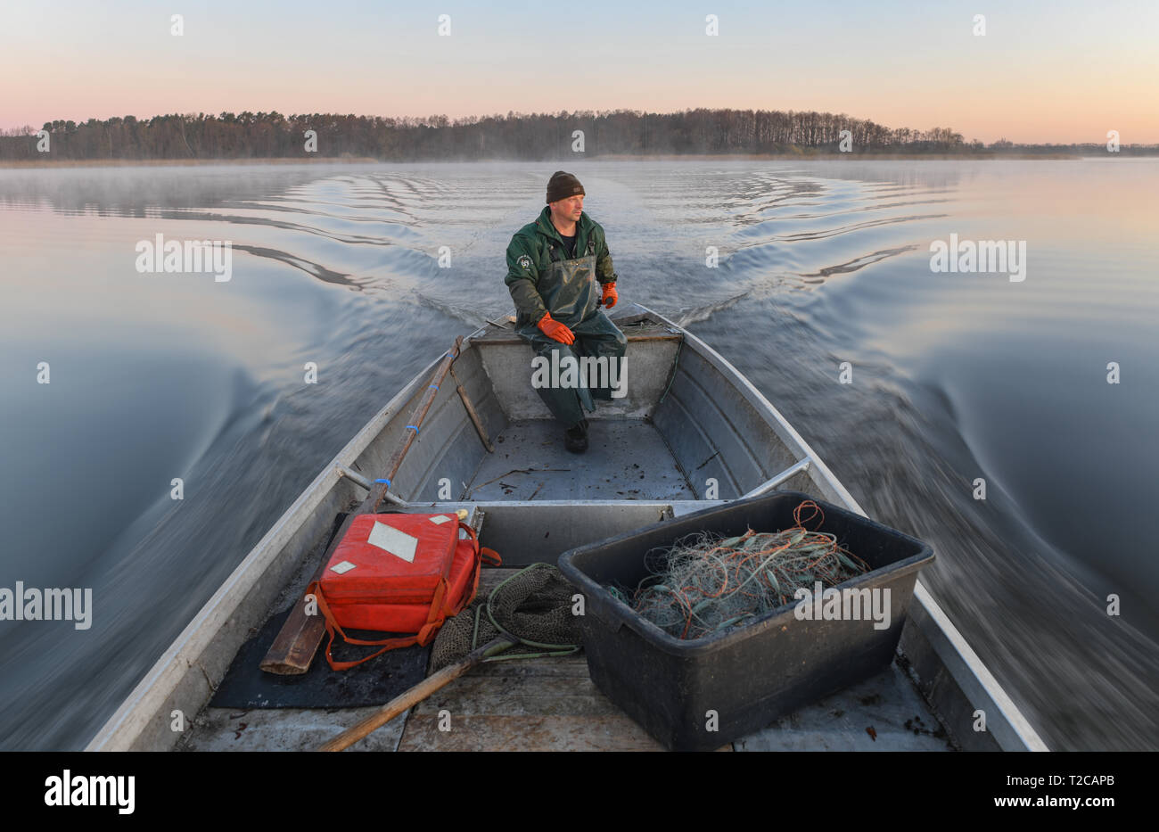 01 aprile 2019, il Land Brandeburgo, Groß Schauen: Laszlo Acz, pescatore di pesca Köllnitz, va nelle prime ore del mattino al sorgere del sole con la sua chiatta su Groß Schauener lago. A circa meno 4 gradi Celsius, il 53-anno-vecchio ha preso nuovamente la sua chiatta per Groß Schauen vedere vicino a Storkow questa mattina per svuotare le trappole e le reti da imbrocco. Oltre a numerosi zander e piombo, che aveva catturato nelle reti da imbrocco, vi era anche un'anguilla in una trappola di pesce. Laszlo Acz originariamente proviene da Ungheria e ha lavorato in Köllnitz pesca per due anni e mezzo. Foto: Patrick Pleul/dpa-Zentralbild/ZB Foto Stock