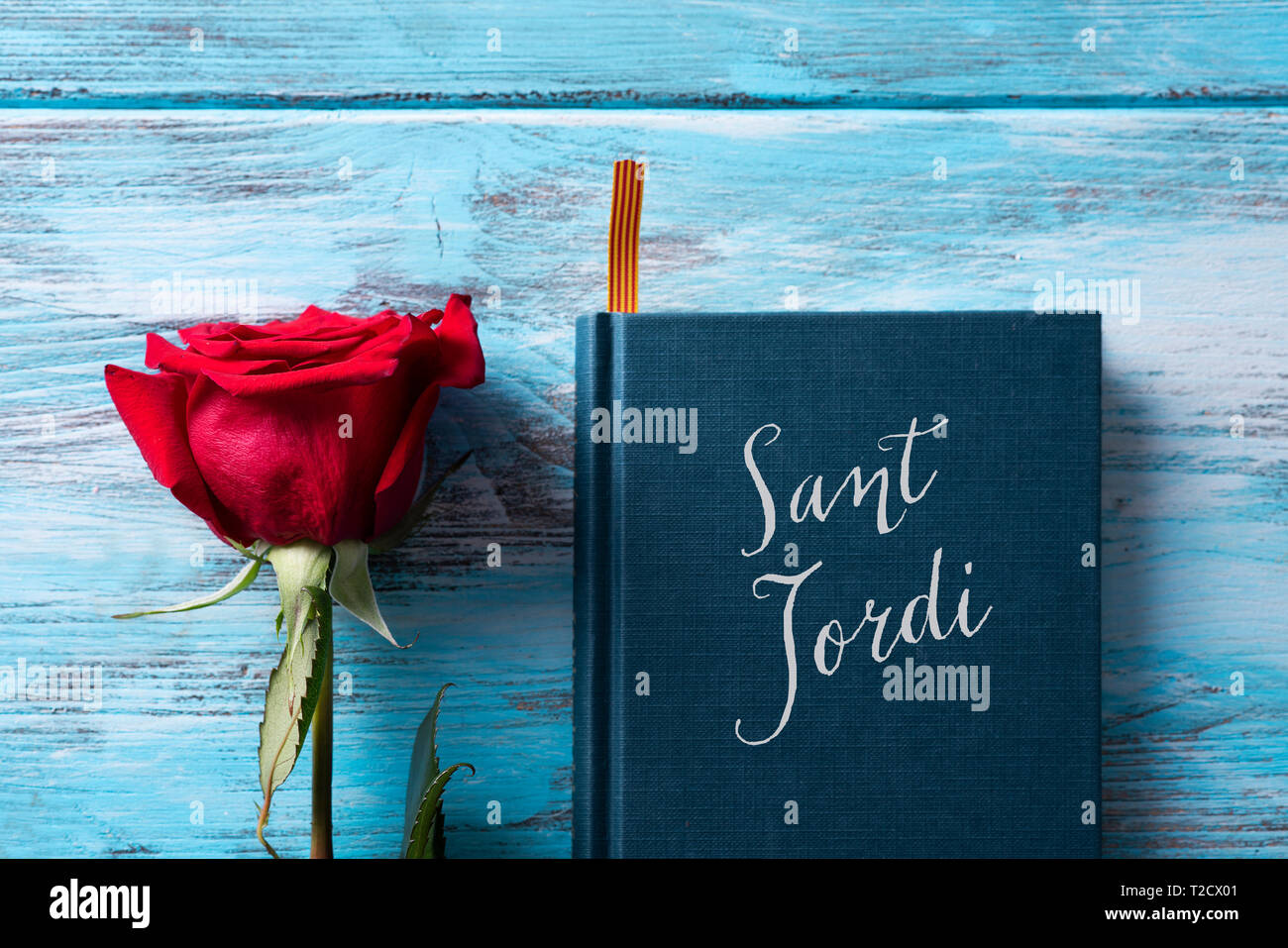 Angolo di alta vista di una rosa rossa e un libro con il testo Sant Jordi, il nome catalano per Saint George giorno, quando è tradizione per dare rose rosse e b Foto Stock