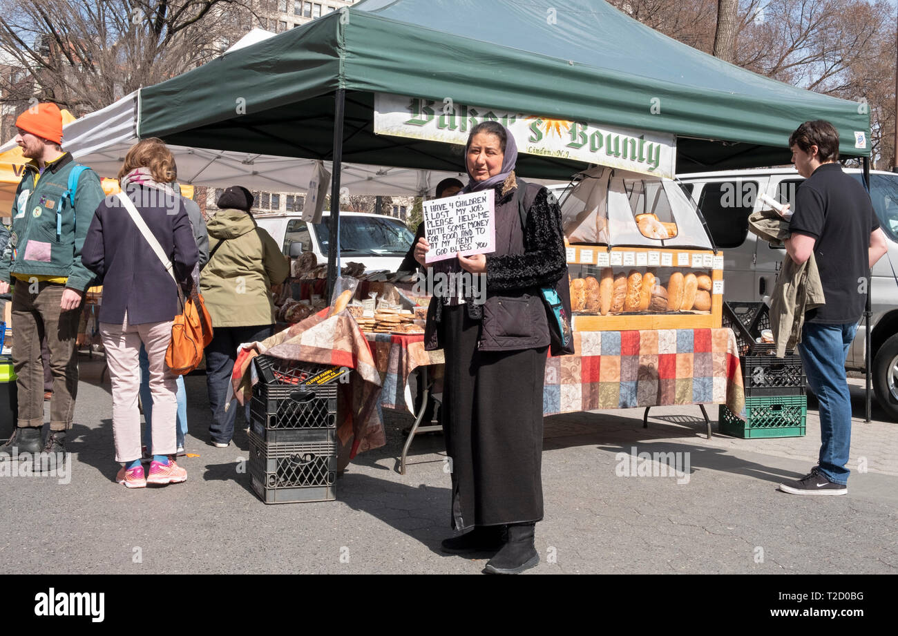 Una donna, eventualmente musulmano, richiedono donazioni per se stessa e i suoi figli all'Unione Piazza Mercato verde a Manhattan, New York City. Foto Stock