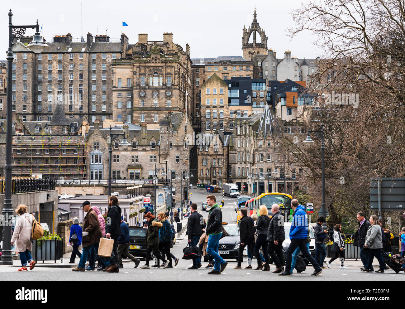 Pedoni che attraversano street con la Città Vecchia alla parte posteriore nel centro di Edimburgo, Scozia, Regno Unito Foto Stock