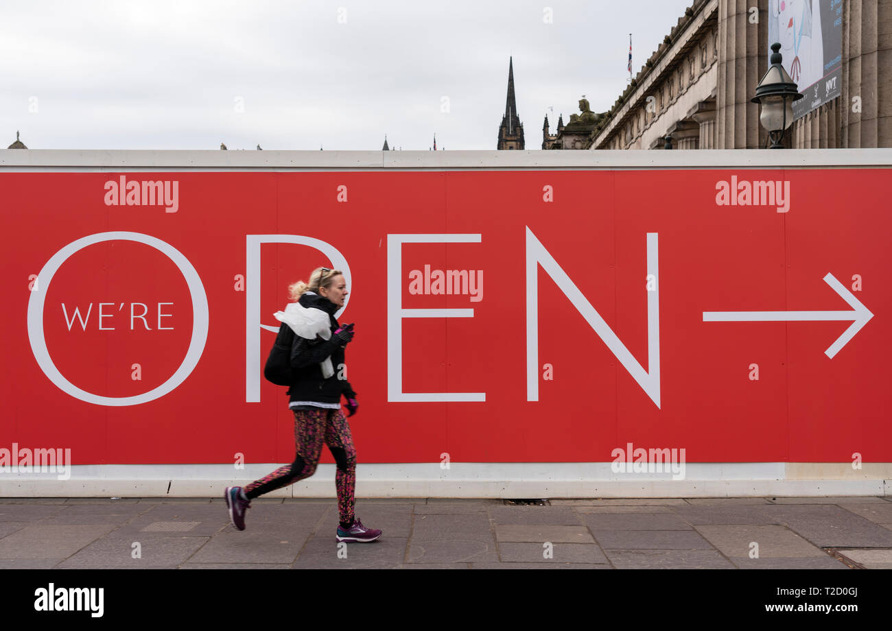 Donna cammina passato billboard al cantiere di restauro i lavori di costruzione della Royal Scottish Academy e Scottish National Gallery musei di arte su Th Foto Stock