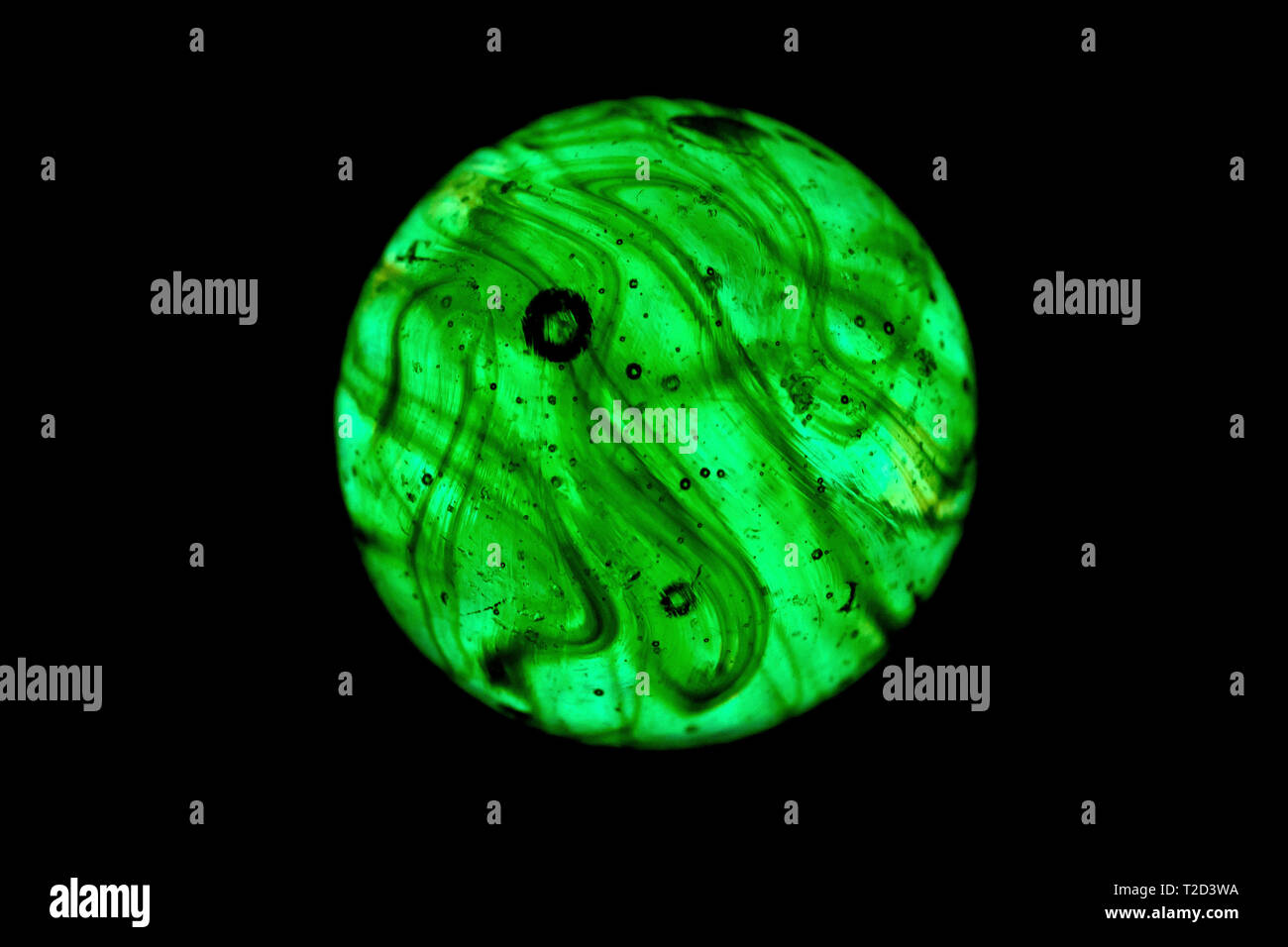 Close up dei pattern all'interno di un retro illuminato verde marmo di vetro su uno sfondo nero. Foto Stock