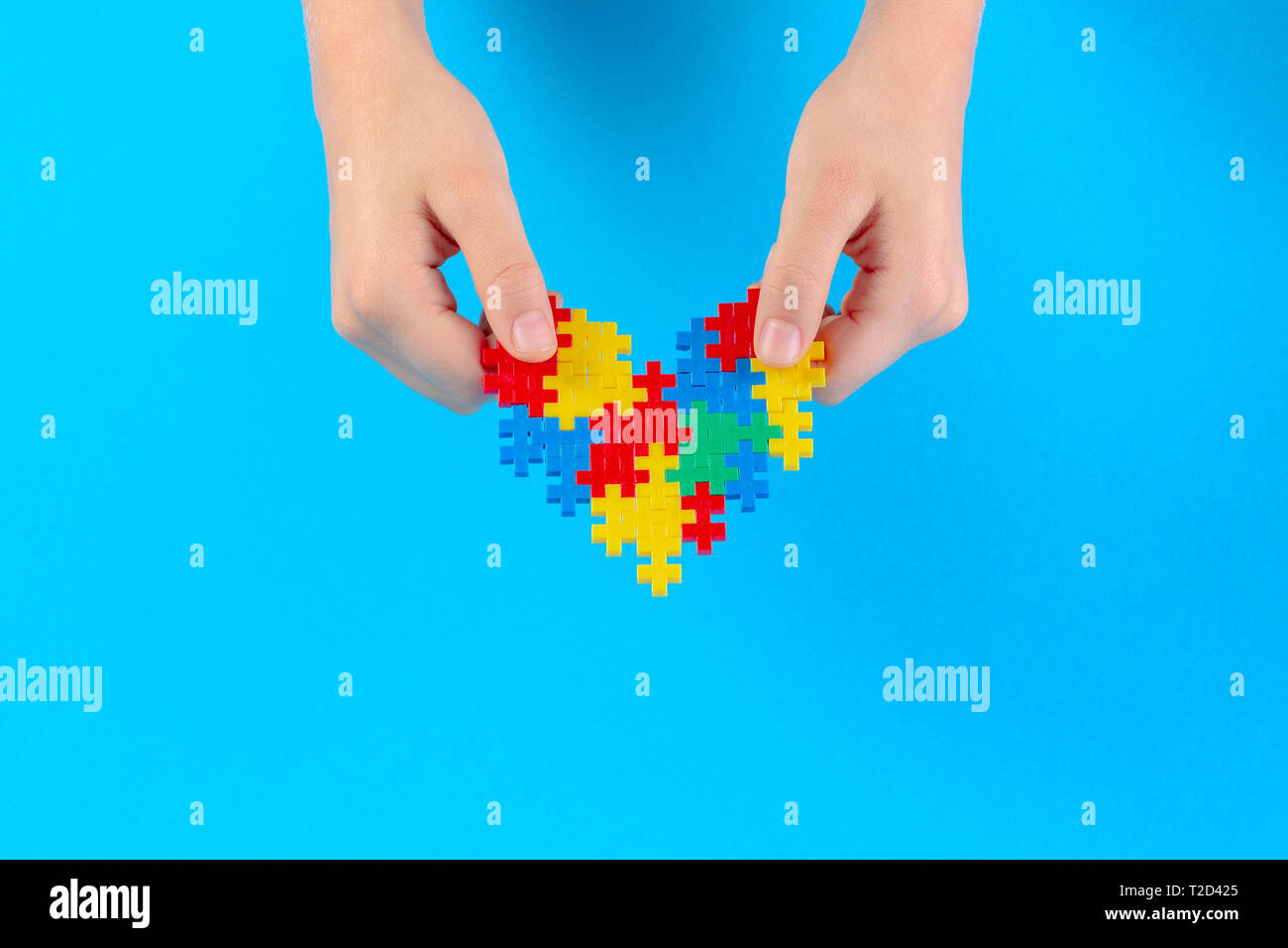 Kid mano azienda cuore colorati su sfondo blu. Mondo autismo consapevolezza giorno di concetto Foto Stock