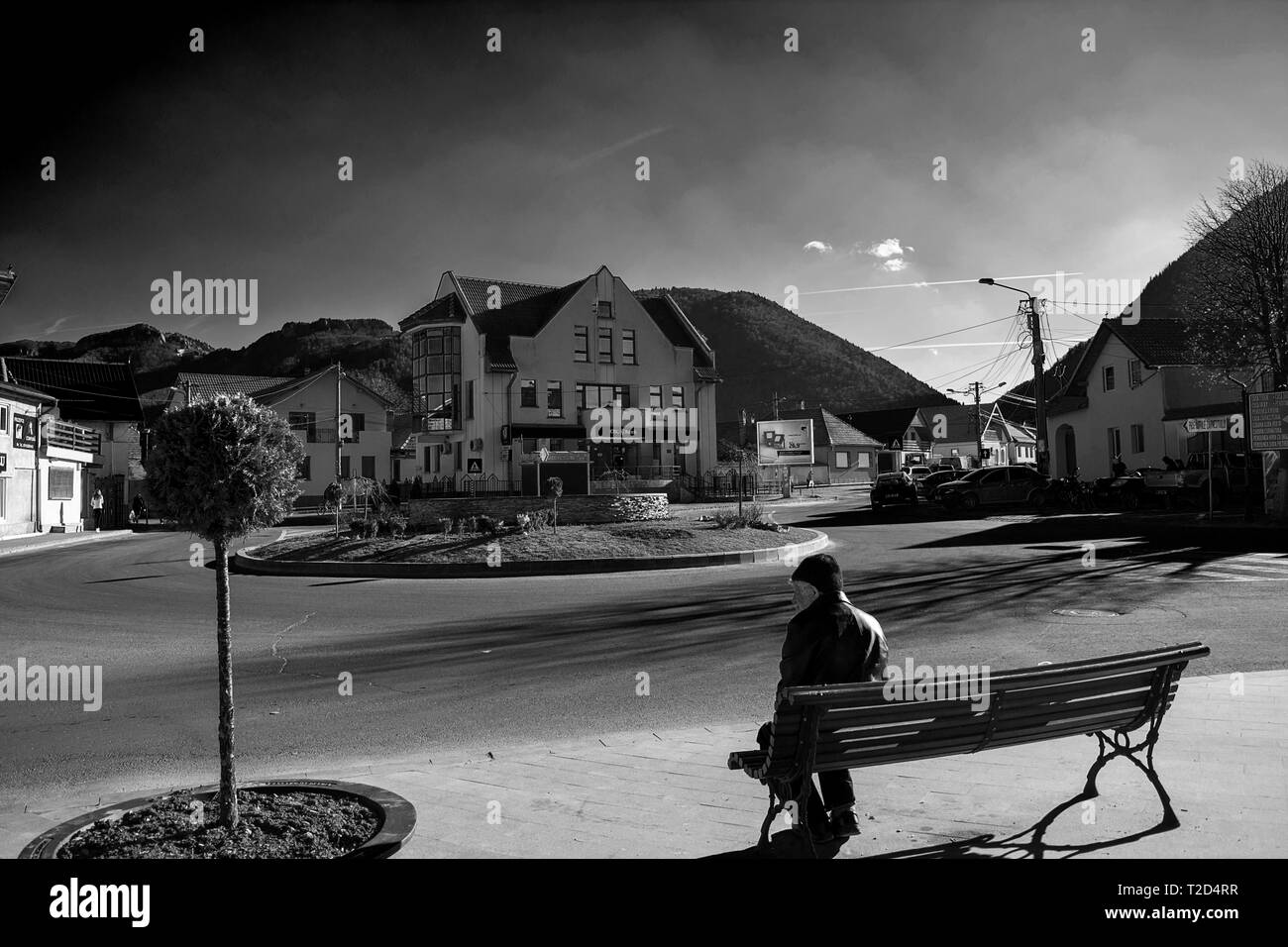 24 marzo 2019-Zarnesti, Romania. Un vecchio uomo seduto sul banco di lavoro e guardando la sua città di residenza Foto Stock