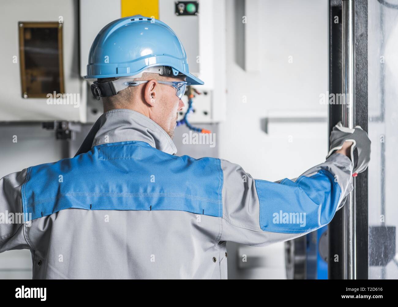 Macchine CNC tecnico. Caucasica lavoratore metalmeccanico nel suo 30s nella parte anteriore del computer di controllo numerico della macchina. Foto Stock