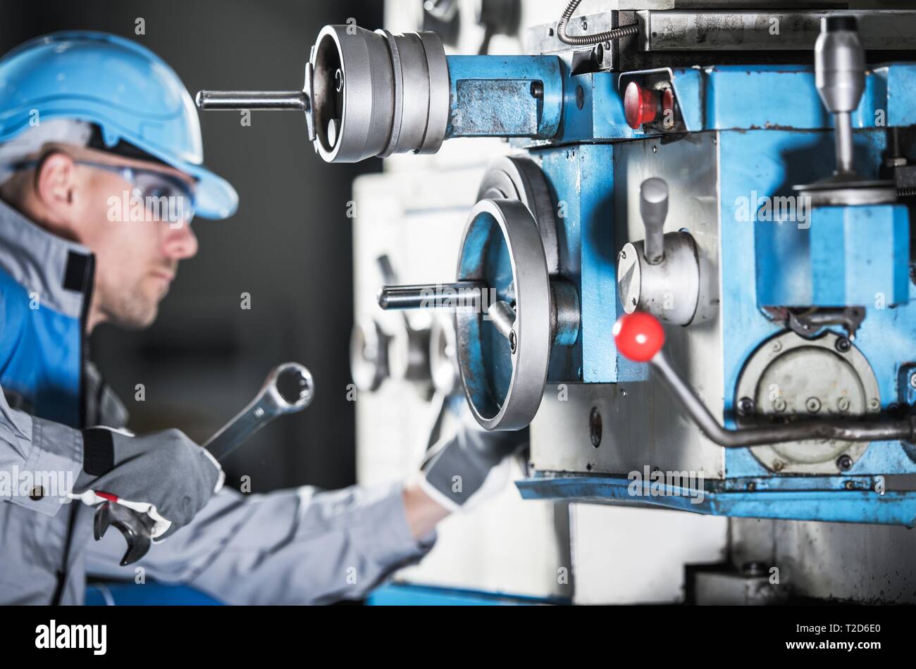 Tornio caucasica Tecnico macchine con una chiave cercando di regolare elementi di macchinari. Industria metallurgica tema. Foto Stock