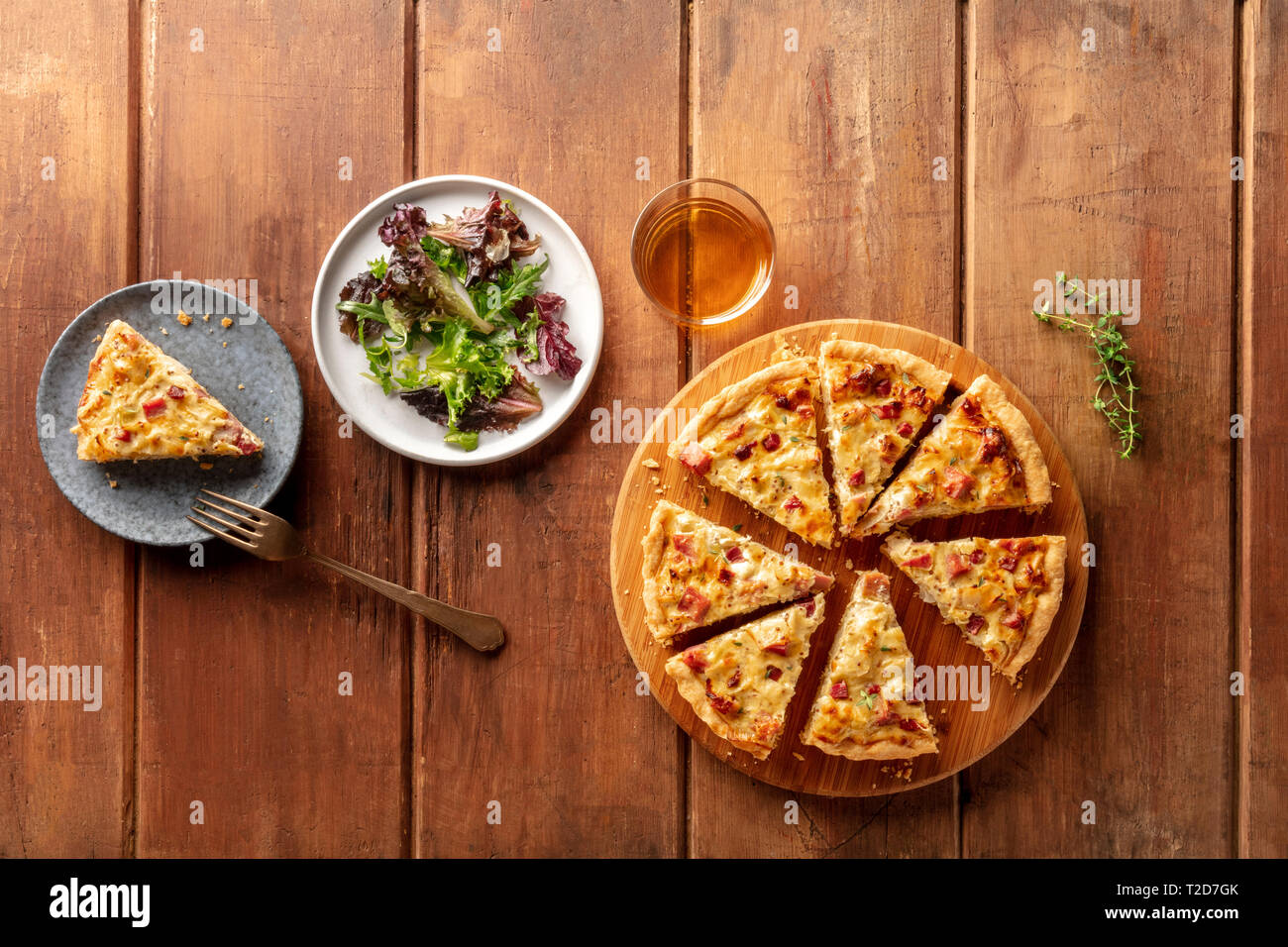 Una foto aerea di una quiche con vino e mesclun foglie di insalata al buio su un rustico sfondo di legno con spazio di copia Foto Stock