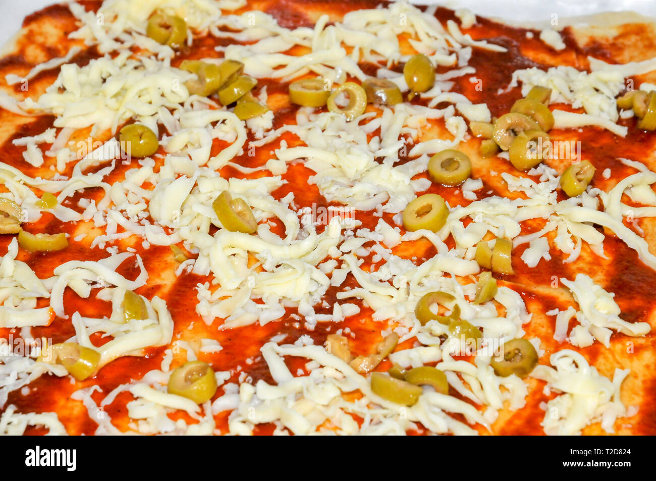 Home pizza fatta di formaggio giallo e le olive vengono poste in salsa di pomodoro Foto Stock