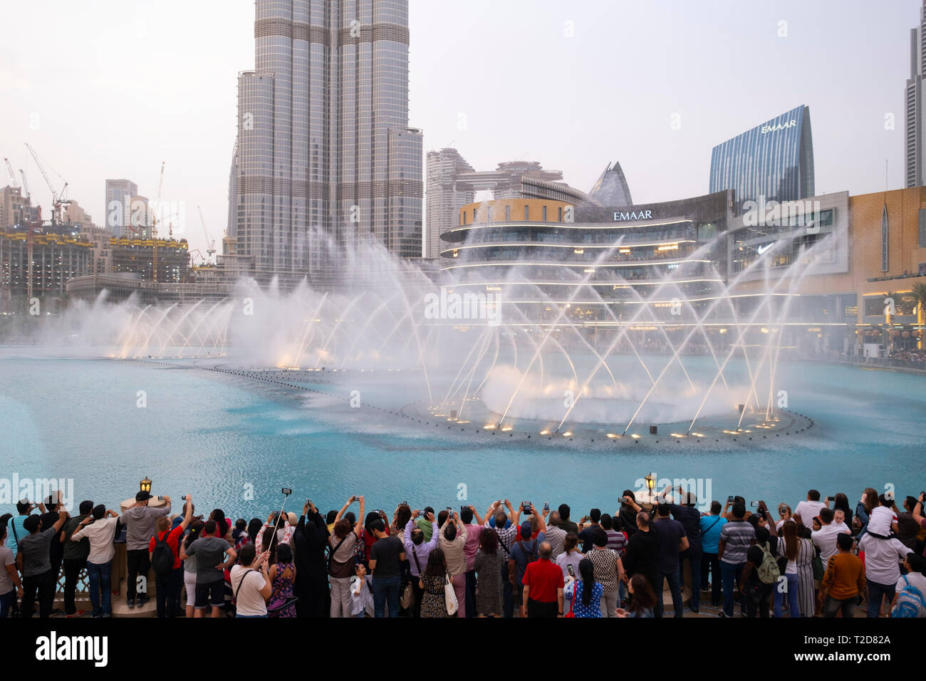 Persone che guardano la sincronizzata getti d'acqua mostrano sul lago di fronte al Burj Khalifa grattacielo a Dubai, Emirati Arabi Uniti Foto Stock