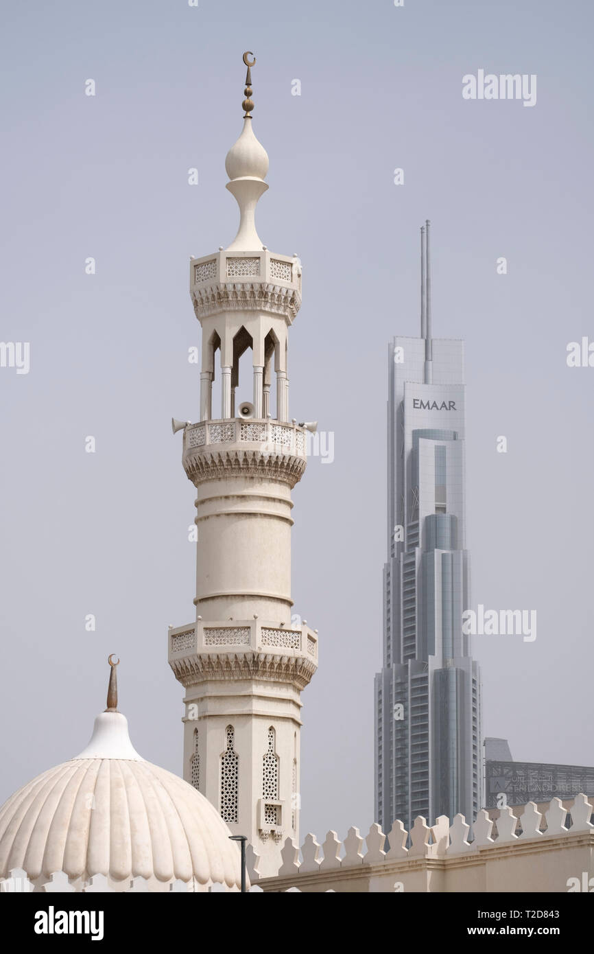 Il vecchio stile musulmano minareto della moschea di fronte ad un design moderno grattacielo di vetro a Dubai, Emirati Arabi Uniti Foto Stock
