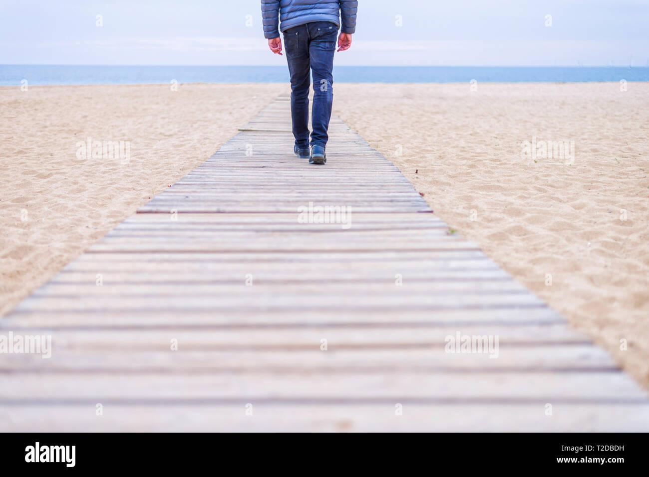 Closep fino dell'uomo gambe per raggiungere a piedi la spiaggia su una tavola di legno pathfoot Foto Stock