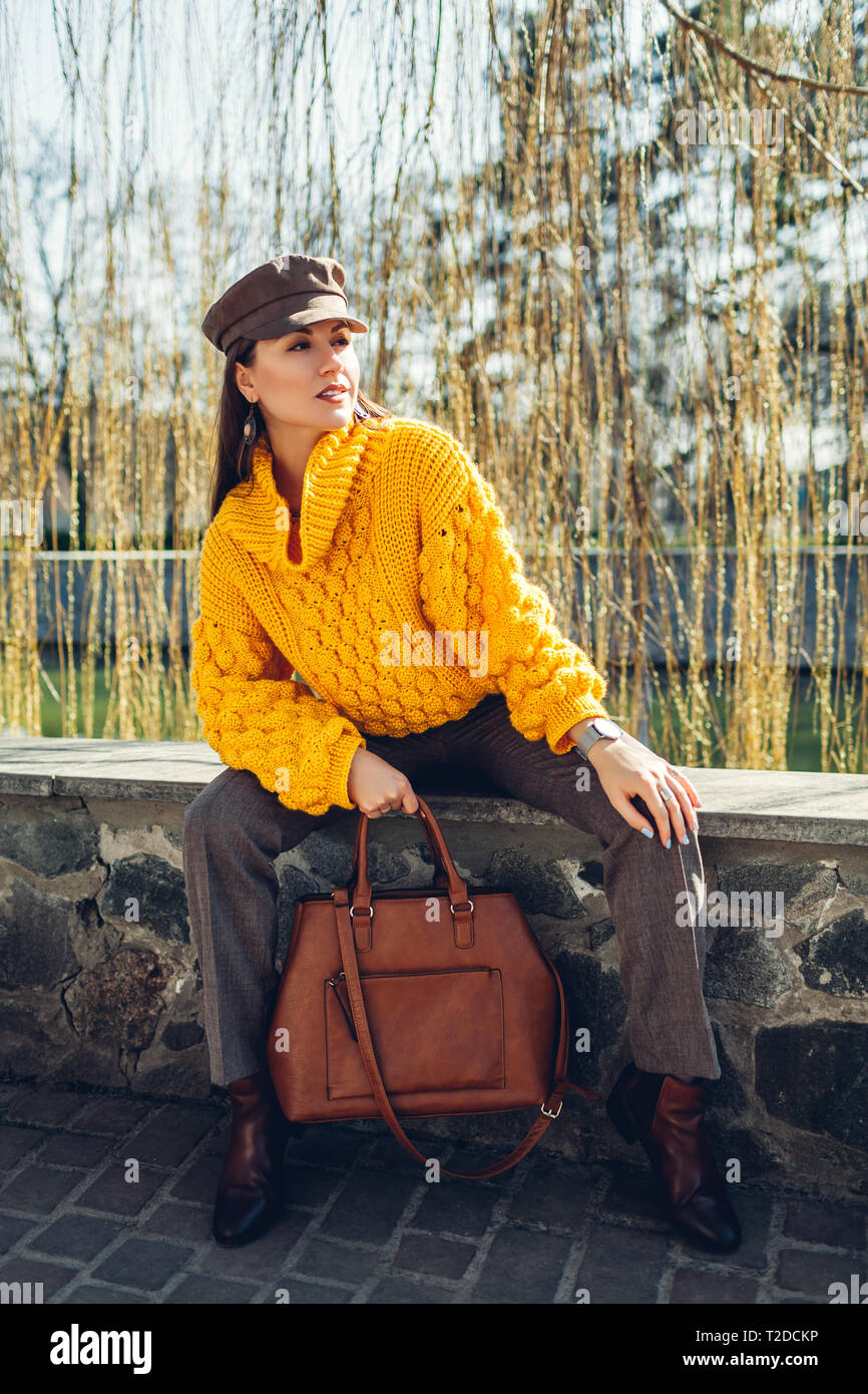 Giovane donna azienda Elegante borsetta e indossa un maglione giallo mentre  guarda guarda. Molla femmina di capi di abbigliamento e accessori. La moda  Foto stock - Alamy