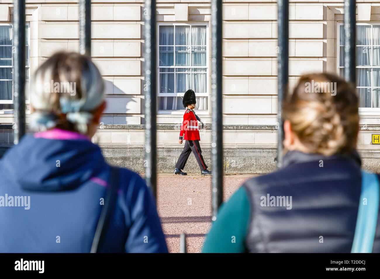 London, Regno Unito - 3 Ottobre 2018 - vista posteriore di due turisti a guardare una sentinella del granatiere guardie di pattuglia fuori Buckingham Palace Foto Stock