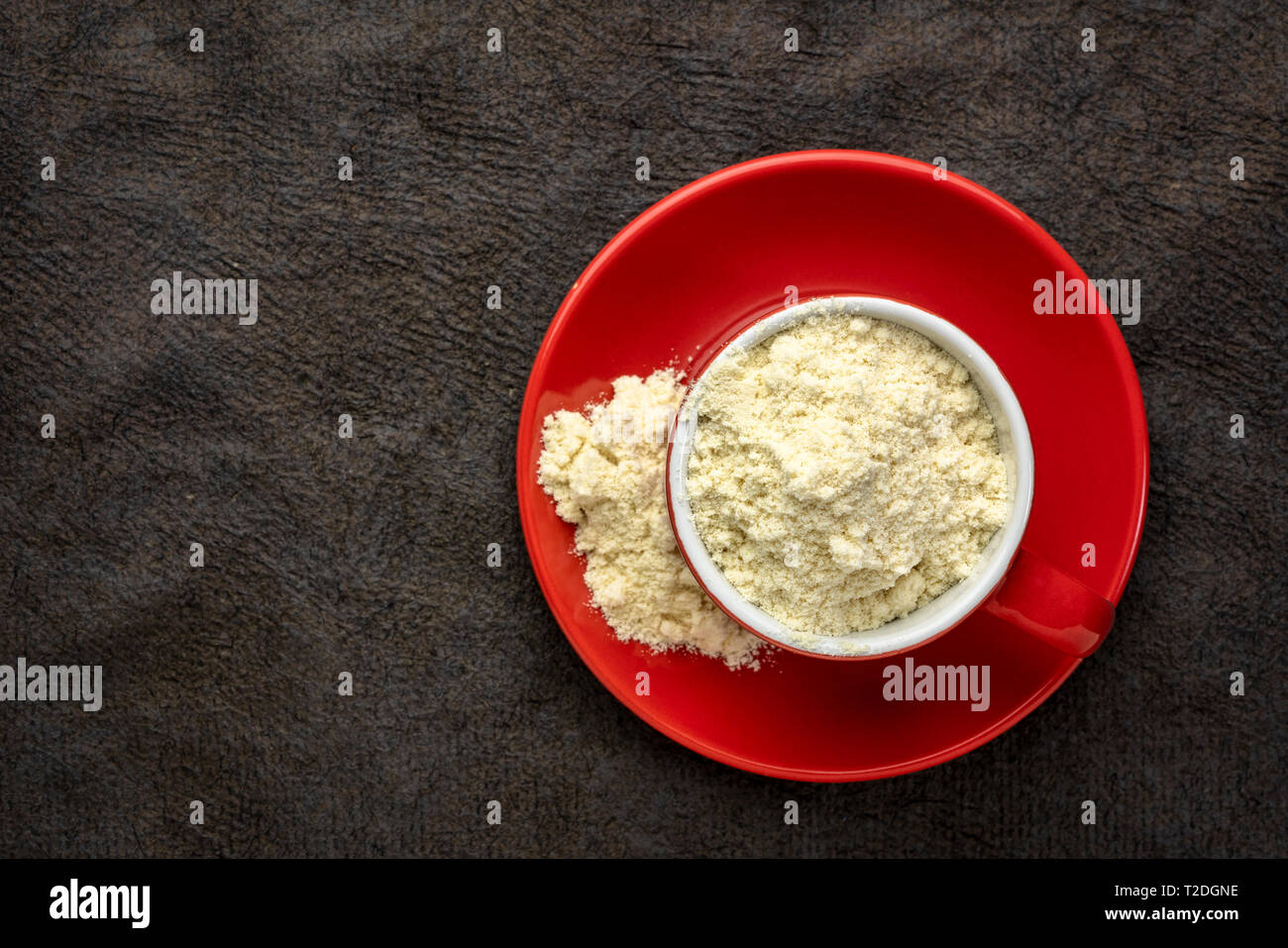 La proteina del siero di latte in polvere in un rosso tazza da caffè contro la trama della carta di corteccia Foto Stock