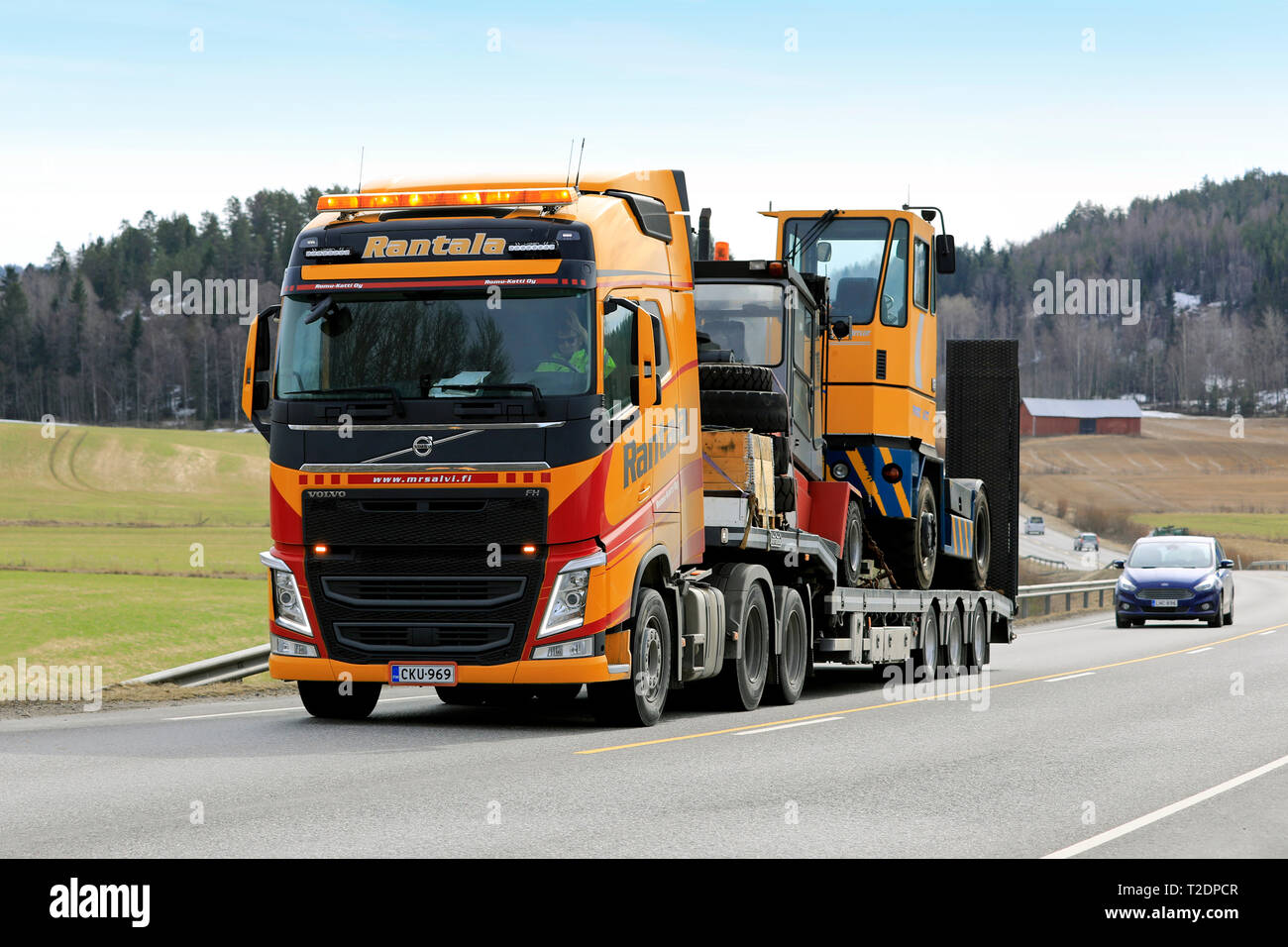 Salo, Finlandia - 29 Marzo 2019: Giallo Volvo Truck FH di Rantala Yhtiot tira terminale di Kalmar il trattore su un rimorchio Noteboom lungo l'autostrada in primavera. Foto Stock