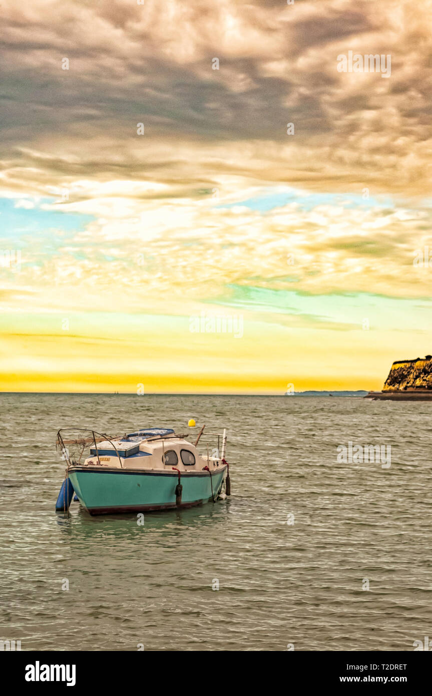 Lone barca ancorata nella baia, la mattina presto con un bel colore giallo sunrise e rotolamento moody di nuvole a Broadstairs Kent, Inghilterra Foto Stock