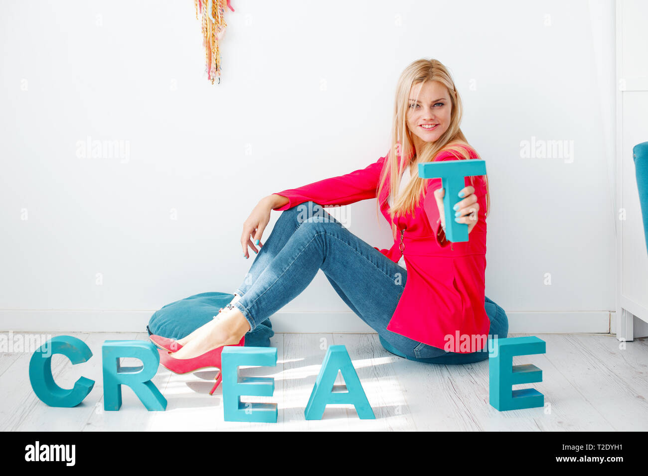 Giovani creativi eleganti donna bionda azienda lettera T sul pavimento Foto Stock