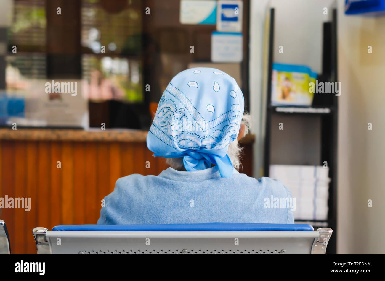 Anziani o persone anziane signora da dietro la seduta in attesa del suo turno in ospedale Foto Stock
