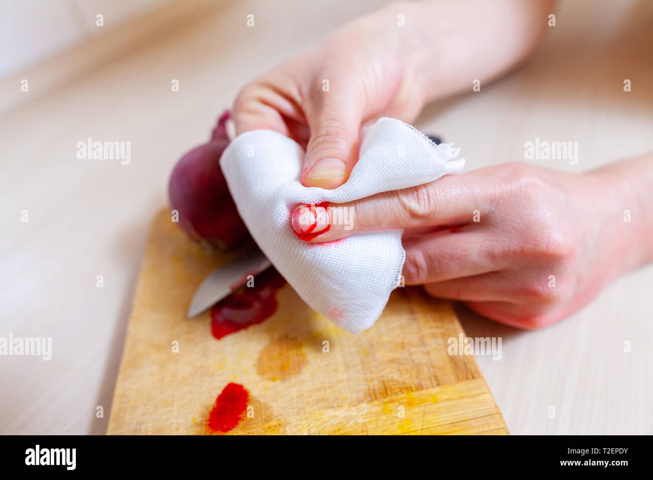Una donna taglia stessa con un coltello da cucina Foto Stock