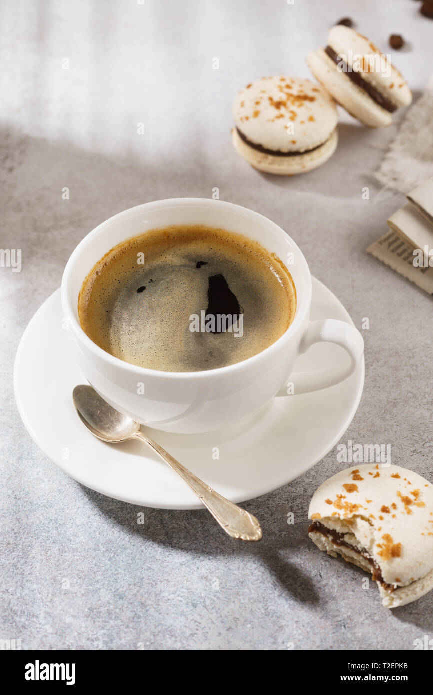 Tazza di caffè nero e cioccolato macarons per dessert. Natural hard light. Foto Stock