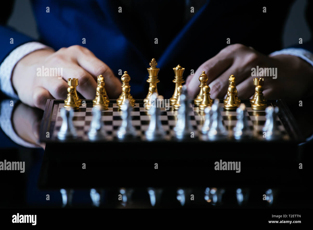 Immagine ritagliata di imprenditore in tuta di pensare sul movimento mentre è seduto al tavolo di vetro e giocare a scacchi Foto Stock