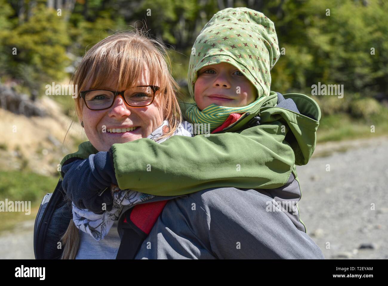 Una donna con un bambino piccolo sulla sua schiena escursionismo, vicino a Ushuaia, Tierra del Fuego, Argentina Foto Stock