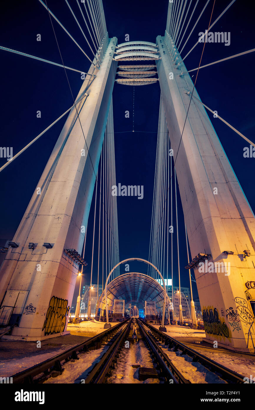 Night Shot di due rotaie utilizzato dal tram per il trasporto pubblico che passa al di sopra di un moderno ponte con alti pilastri durante il periodo invernale in Bucharest Romania Foto Stock