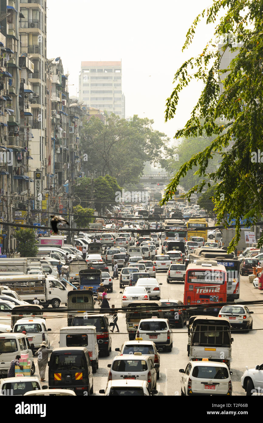 Il traffico giornaliero e la vita della città su strade trafficate di Yangon durante il tramonto. Yangon è la capitale della regione di Yangon Foto Stock