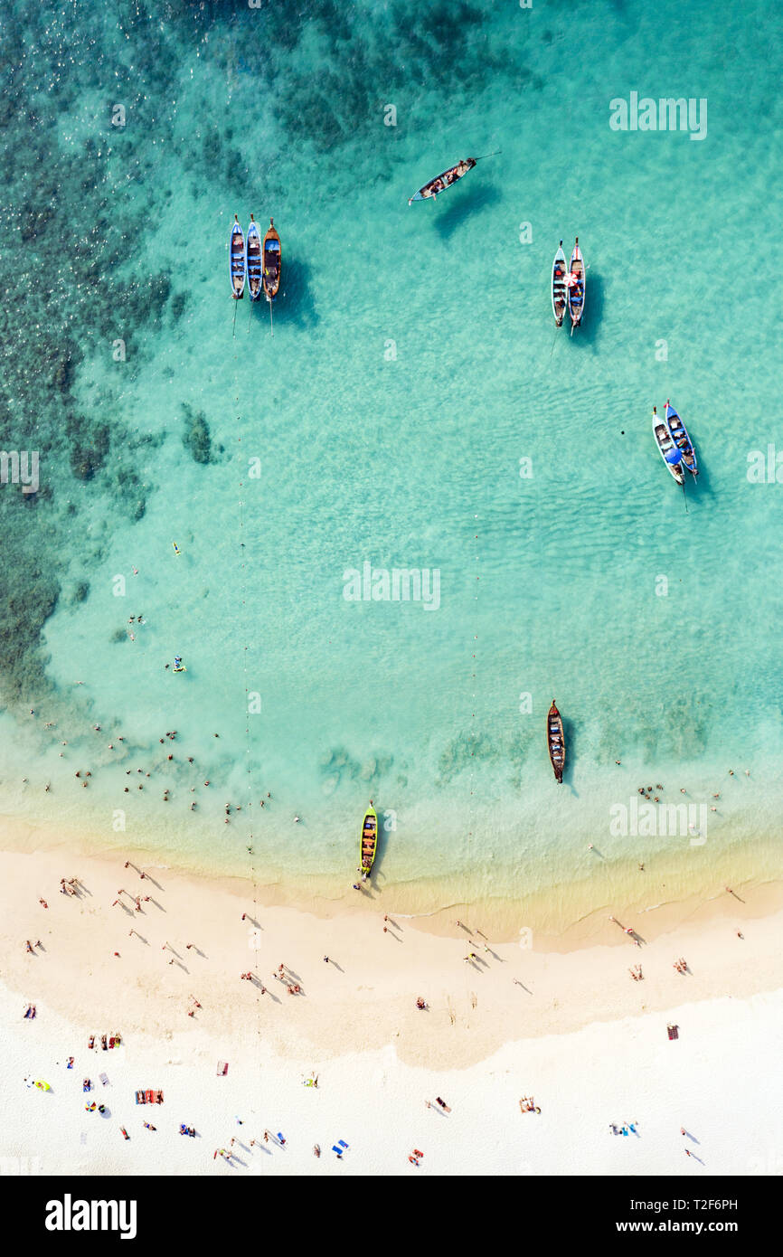 Vista da sopra, vista aerea di una bella spiaggia tropicale con sabbia bianca e turchesi acque chiare, coda lunga barche e le persone sole. Foto Stock