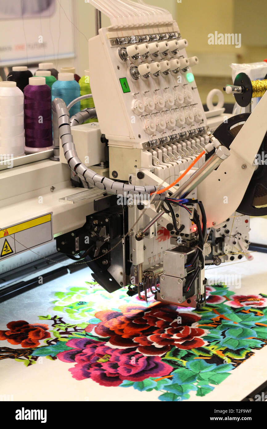 Manifattura Tessile. La macchina ricama un disegno floreale. La fabbrica per la produzione di capi di abbigliamento. Foto Stock